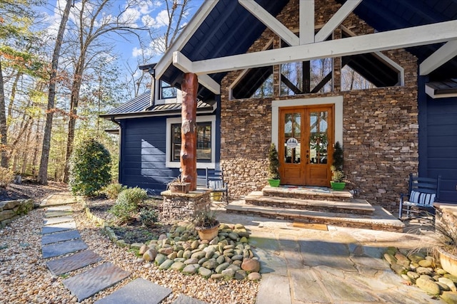 property entrance with metal roof, stone siding, and french doors