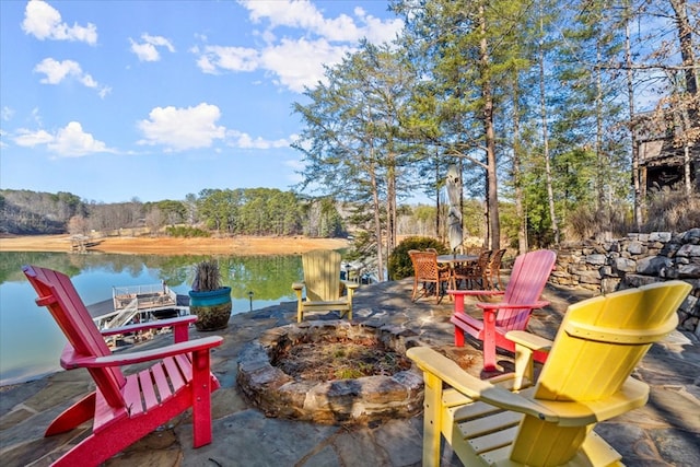 view of patio / terrace with a fire pit, a water view, and a wooded view