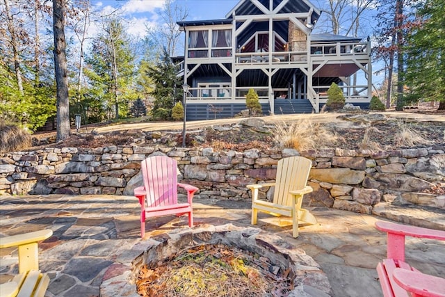 back of house featuring a patio, an outdoor fire pit, a sunroom, a wooden deck, and stairs