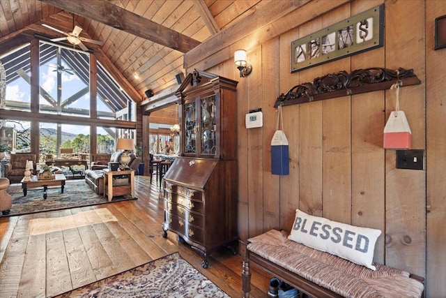 sitting room with wooden ceiling, ceiling fan, wood finished floors, beamed ceiling, and wood walls