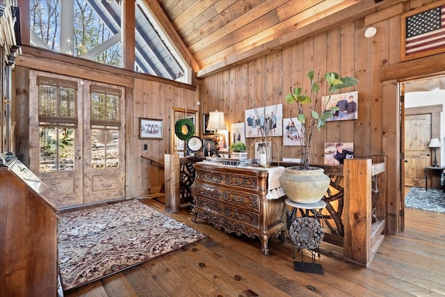 entrance foyer with wood walls, plenty of natural light, wood finished floors, and french doors