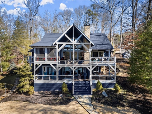 view of front of house with stone siding, a chimney, stairway, and metal roof