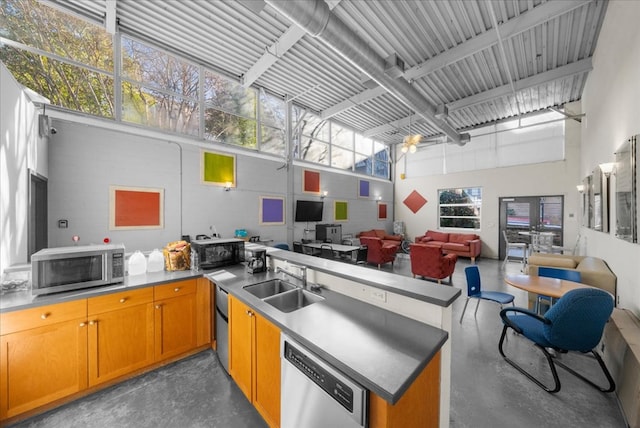 kitchen featuring a towering ceiling, appliances with stainless steel finishes, and sink