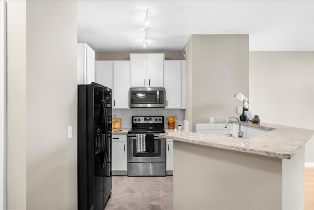 kitchen featuring white cabinetry, light stone counters, appliances with stainless steel finishes, kitchen peninsula, and decorative backsplash