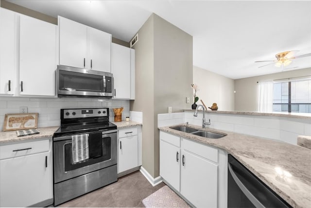 kitchen featuring sink, stainless steel appliances, light stone counters, white cabinets, and decorative backsplash