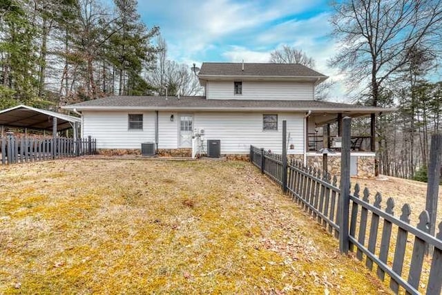 rear view of house with a carport, central AC unit, and a lawn