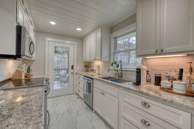 kitchen with sink, light stone counters, appliances with stainless steel finishes, decorative backsplash, and white cabinets