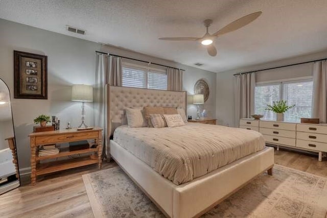 bedroom with ceiling fan, a textured ceiling, and light wood-type flooring