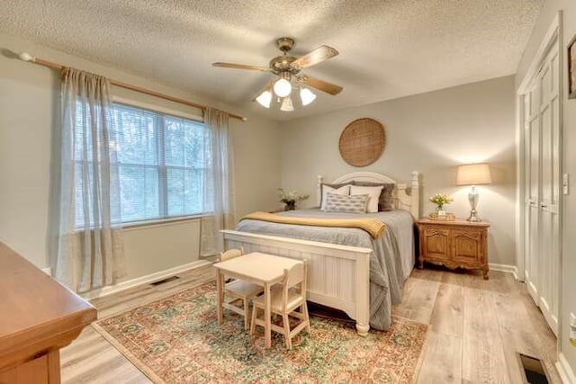 bedroom with ceiling fan, a textured ceiling, and light wood-type flooring