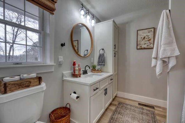 bathroom featuring lofted ceiling, hardwood / wood-style flooring, vanity, a textured ceiling, and toilet