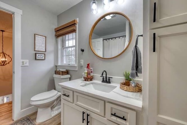 bathroom featuring vanity, wood-type flooring, toilet, and an inviting chandelier