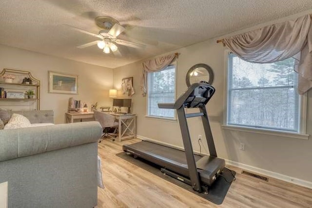 workout room with ceiling fan, a textured ceiling, and light wood-type flooring