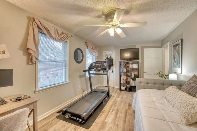 exercise area with ceiling fan, a textured ceiling, and light hardwood / wood-style floors