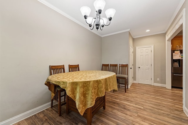 dining area featuring wood-type flooring, crown molding, and a chandelier