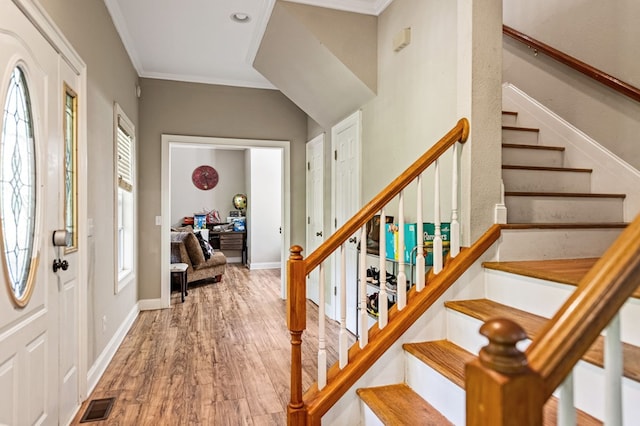 entryway with ornamental molding and hardwood / wood-style floors