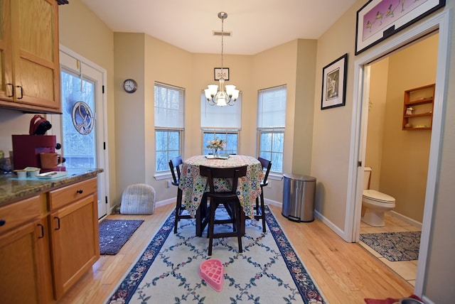 dining area featuring a healthy amount of sunlight, a chandelier, and light hardwood / wood-style flooring