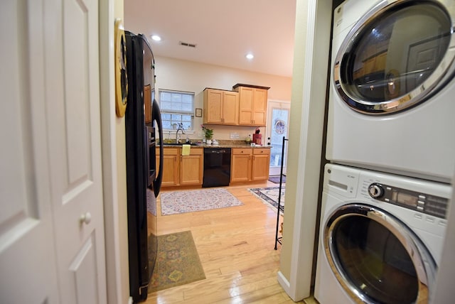 laundry room with stacked washer and clothes dryer and light wood-type flooring