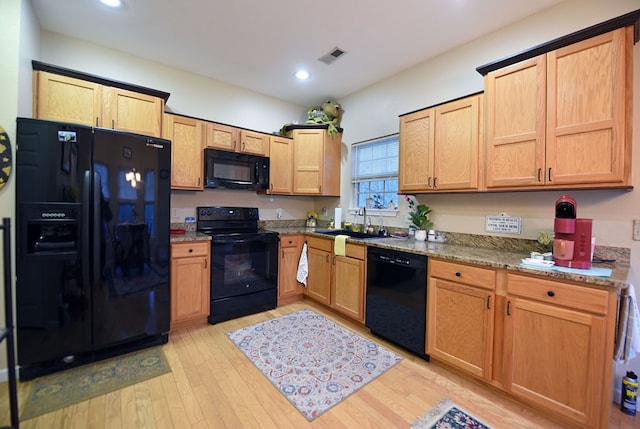 kitchen with light stone countertops, sink, light hardwood / wood-style flooring, and black appliances