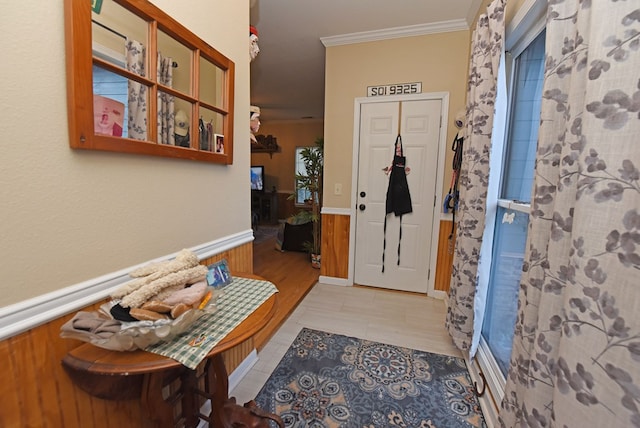 foyer entrance featuring crown molding, wooden walls, and light tile patterned flooring