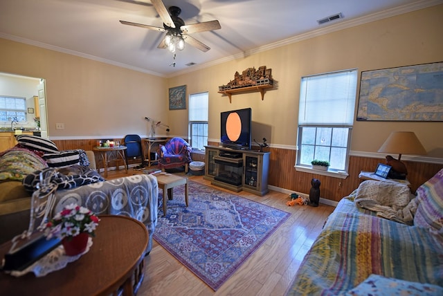 living room featuring hardwood / wood-style floors, ornamental molding, ceiling fan, and wood walls