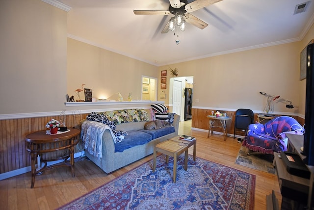 living room with crown molding, ceiling fan, wooden walls, and hardwood / wood-style flooring