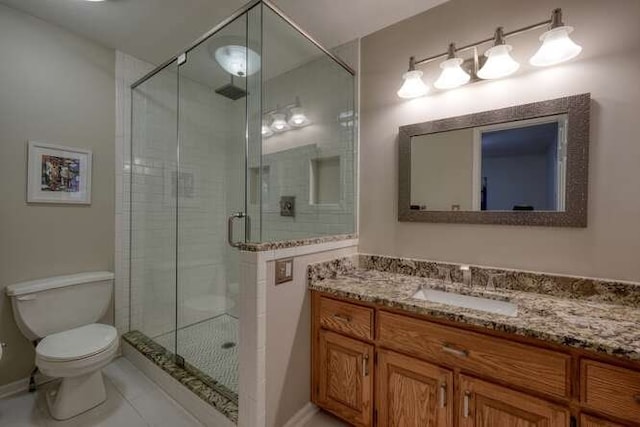 bathroom featuring tile patterned flooring, a shower with door, vanity, and toilet