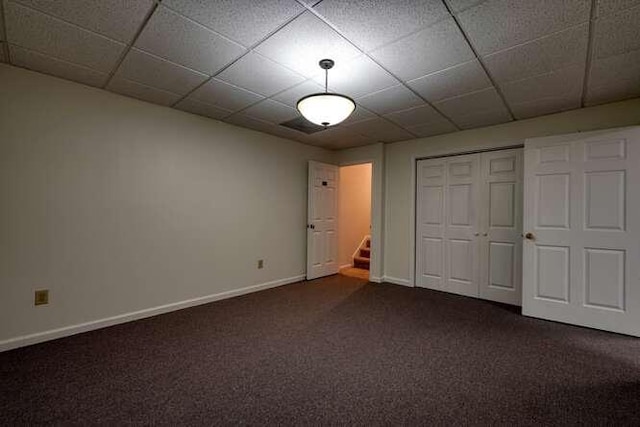 unfurnished bedroom with a paneled ceiling, a closet, and dark carpet