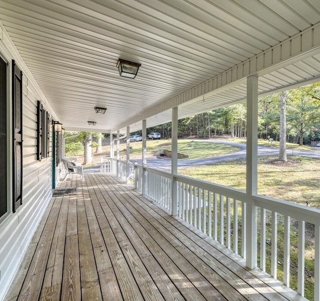 wooden terrace featuring a yard and a porch