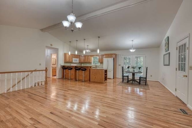 living room featuring vaulted ceiling with beams, light hardwood / wood-style floors, and an inviting chandelier