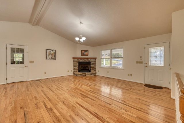 unfurnished living room featuring a stone fireplace, a notable chandelier, lofted ceiling with beams, and light hardwood / wood-style floors