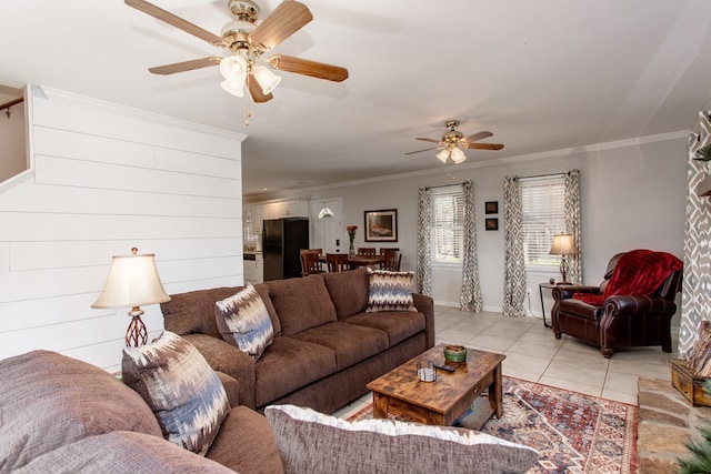 living room featuring light tile patterned floors, baseboards, crown molding, and a ceiling fan