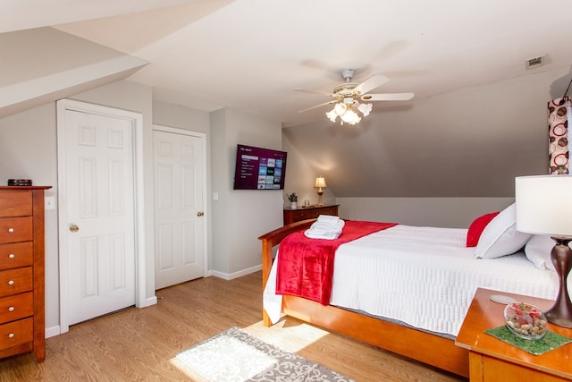 bedroom with a ceiling fan, wood finished floors, visible vents, baseboards, and vaulted ceiling