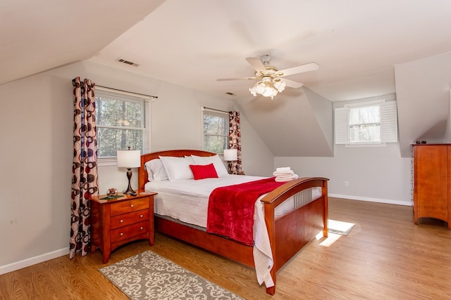 bedroom featuring visible vents, ceiling fan, baseboards, lofted ceiling, and wood finished floors