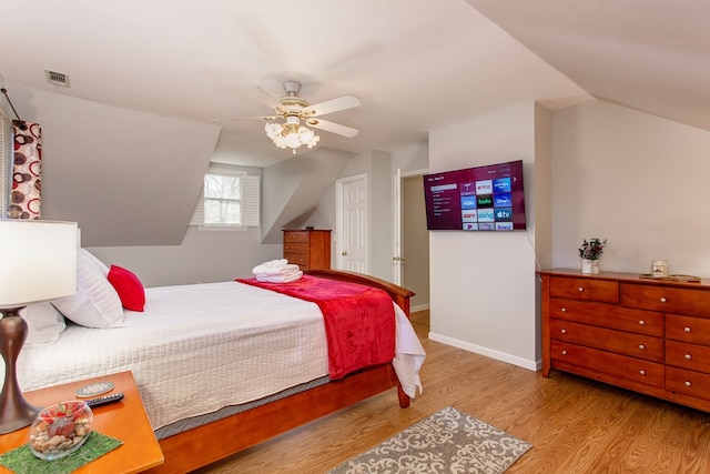 bedroom featuring visible vents, wood finished floors, baseboards, ceiling fan, and vaulted ceiling