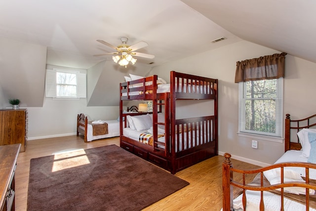 bedroom featuring visible vents, baseboards, lofted ceiling, and wood finished floors