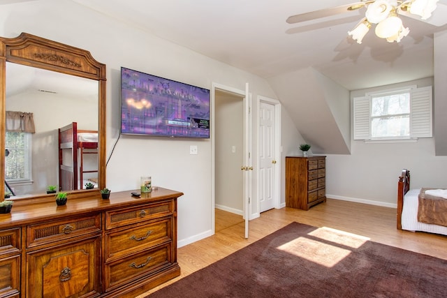 bedroom with vaulted ceiling, wood finished floors, and baseboards