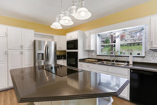 kitchen with dark countertops, backsplash, black appliances, white cabinetry, and a sink