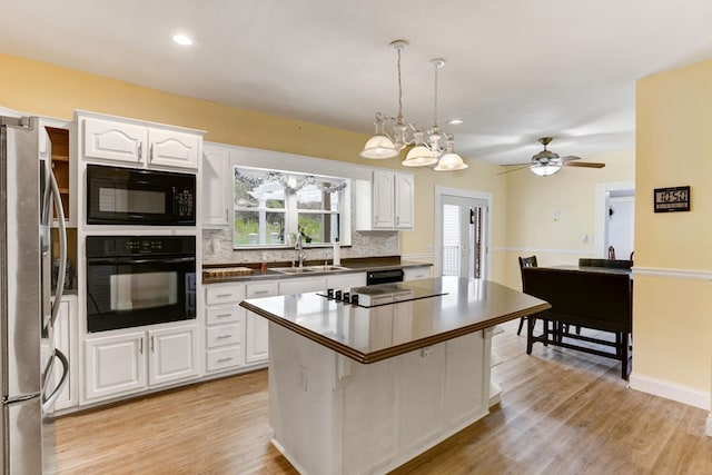 kitchen with a sink, white cabinetry, black appliances, and light wood finished floors