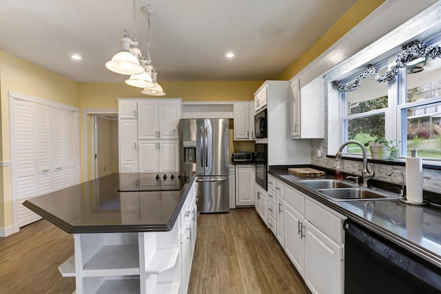 kitchen with dark wood-style flooring, a sink, black appliances, white cabinetry, and dark countertops