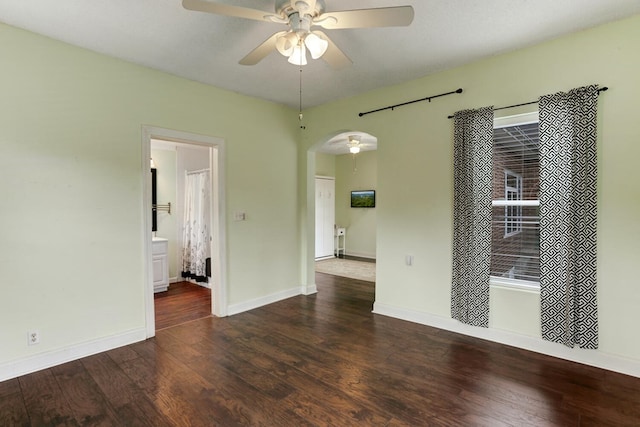 unfurnished room with arched walkways, baseboards, a ceiling fan, and wood finished floors