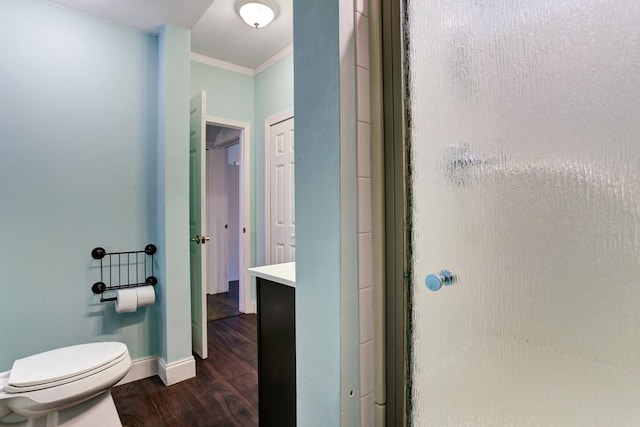 bathroom with a shower stall, crown molding, baseboards, toilet, and wood finished floors