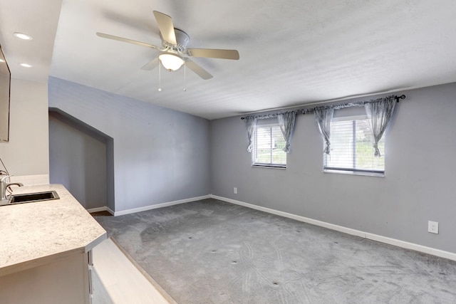 interior space with ceiling fan, carpet flooring, baseboards, and a sink