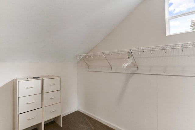 walk in closet with dark carpet and vaulted ceiling