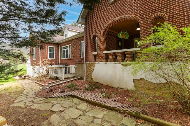 view of home's exterior featuring a ceiling fan and brick siding