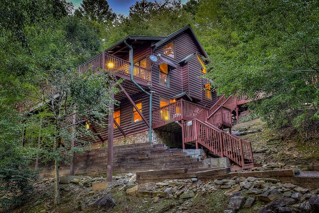 back house at dusk featuring a deck