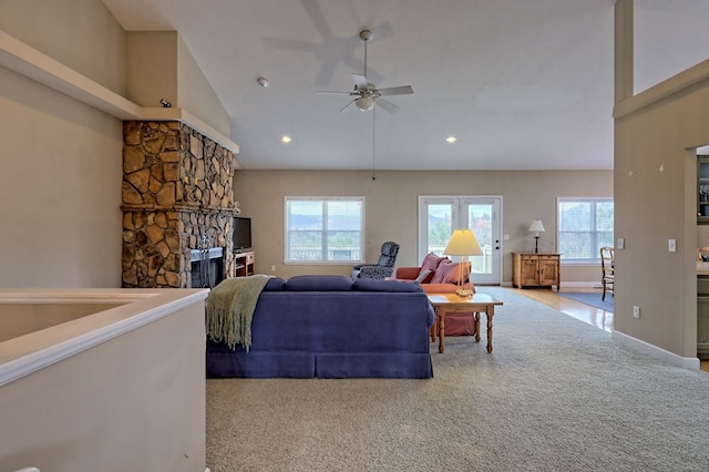 living room with a fireplace, high vaulted ceiling, a healthy amount of sunlight, and light colored carpet