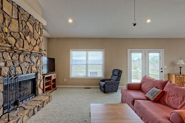 carpeted living room with a stone fireplace