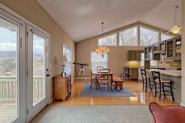 dining room featuring ceiling fan with notable chandelier, lofted ceiling, and light wood-type flooring