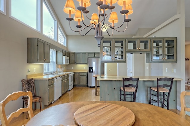 kitchen featuring light hardwood / wood-style flooring, pendant lighting, a chandelier, white appliances, and gray cabinets