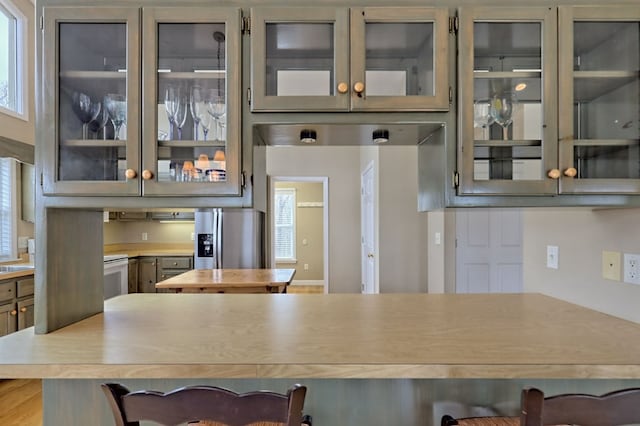 kitchen featuring a kitchen breakfast bar, gray cabinets, stainless steel refrigerator with ice dispenser, and hardwood / wood-style flooring